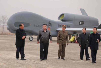 Kim Jong Un (dua dari kiri) sedang memeriksa pesawat pengintipan tanpa pemandu yang baru dibangunkan di lokasi yang tidak didedahkan di Korea Utara. Foto AFP