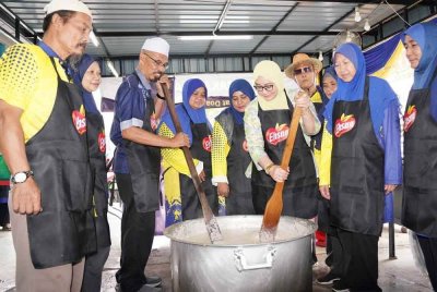 Muhamad Othman (tiga dari kiri) dan Noor Azreena (tiga dari kanan) memasak bubur lambuk di Masjid An-Naim, Jalan Kebun, Shah Alam.