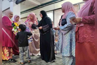 Mas Ermieyati (tiga dari kiri) dan Roseniza (dua dari kiri) menyampaikan sumbangan kepada salah seorang kanak-kanak yang diraikan pada Majlis Iftar Bersama Anak Yatim di Pusat Khidmat Srikandi Bersatu Melaka di Tambak Paya pada Jumaat.