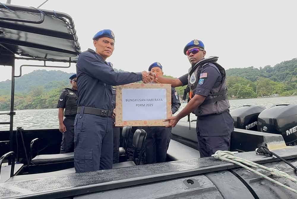 Rusley (kiri) menyampaikan Bungkusan Raya PDRM 2025 kepada anggota Pasukan Polis Marin pada Khamis.