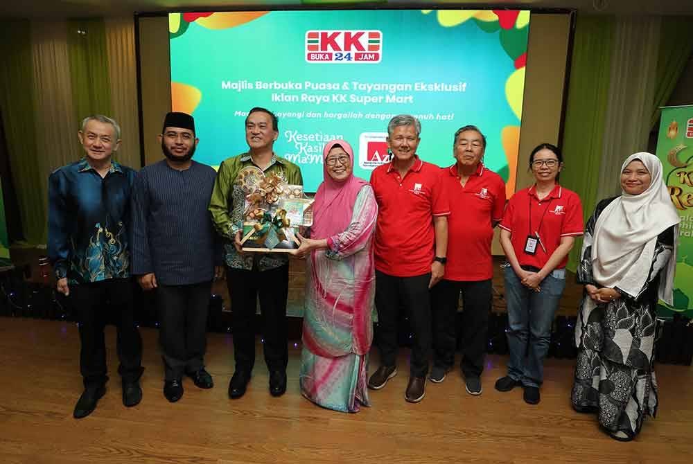 Chai (tiga dari kiri) menyerahkan cenderahati kepada Pengerusi Jawatankuasa Eksekutif ADFM, Tan Sri Hasmah Abdullah (lima dari kanan) ketika Majlis Berbuka Puasa dan Tayangan Eksklusif Iklan Raya KK Super Mart baru-baru ini.