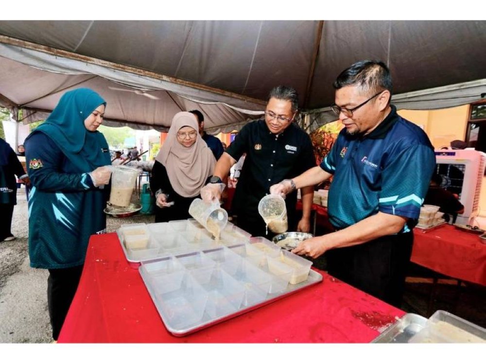 KEDAH - Ketua Pegawai Kewangan PTPTN, Azhar Ahmad (dua dari kanan) menyediakan hidangan bubur lambuk sambil dibantu Pengarah Kolej Komuniti, Dr Reezlin Abd Rahman untuk diagihkan kepada para pelajar.