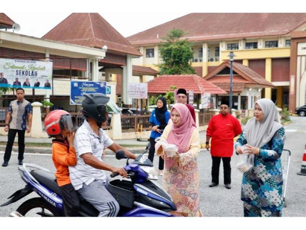PUTRAJAYA - PENGURUSI PTPTN, Datuk Seri Norliza Abdul Rahim (Tengah) turun padang semasa sesi pengagihan bubur lambuk bersama penduduk sekitar Sekolah Menengah Kebangsaan Presint 14 (1) diiringi oleh Pengurus Besar Kanan, Jabatan Komunikasi Korporat dan Pemasaran PTPTN, Wan Zawiah Wan Abu Bakar (kanan).