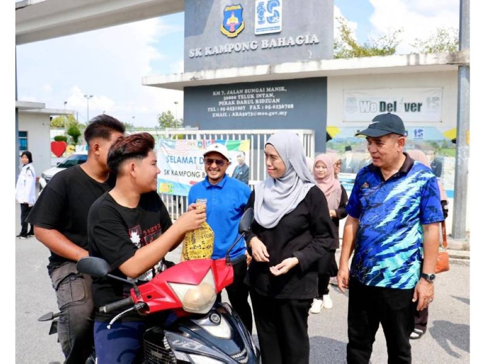 PERAK - Ketua Pegawai Operasi PTPTN, Mastura Mohd Khalid (dua dari kanan) bersama Pengarah Negeri PTPTN Perak, Andi Nurali Mohamed (tengah) dan Pegawai Pendidikan Daerah Hilir Perak, Shamsuddin Tajul Urus mengagihkan bubur lambuk kepada penduduk sekitar Kampung Bahagia, Teluk Intan.