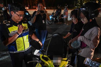 Pengarah Jabatan Pengangkutan Jalan (JPJ) Terengganu, Zamri Samion (kiri) memeriksa dokumen perjalanan penunggang dalam Operasi Khas Motosikal Sempena Hari Raya Aidilfitri 2025 (OPS HRA 2025) di Jalan Kemajuan, malam Khamis. Foto Bernama