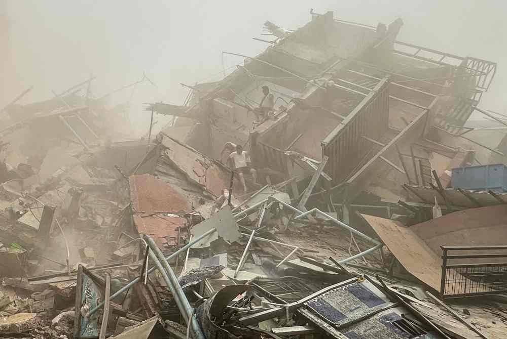 Orang ramai memeriksa runtuhan bangunan yang roboh di Mandalay selepas kejadian gempa bumi. Foto AFP