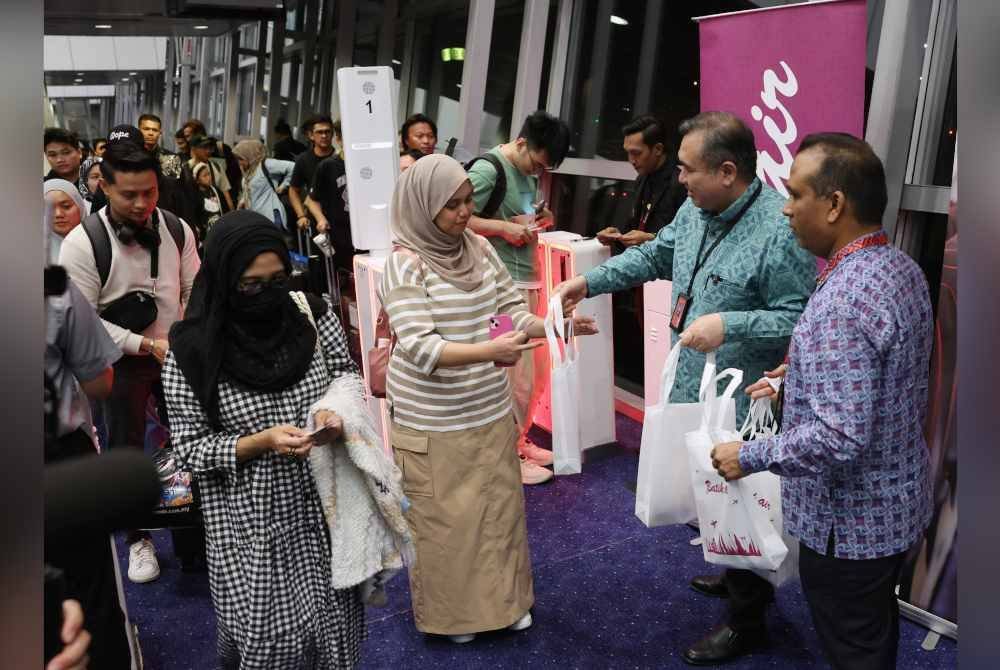 Anthony (dua, kanan) menyampaikan goodies raya kepada penumpang pesawat Batik Air OD 7908 ke Tawau di KLIA Terminal 1 pada Jumaat. Foto Bernama