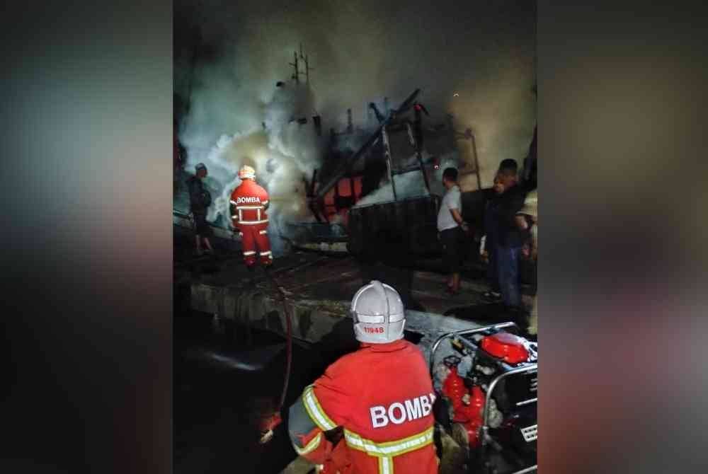 Anggota bomba memadamkan api dalam kebakaran membabitkan sebuah bot laut dalam di Kampung Genting, Tumpat pada Jumaat.