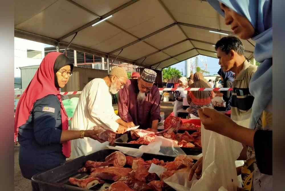 Syed Abu Hussin (dua dari kiri) turut membantu membuat jualan kepada orang ramai sempena JTM Aidilfitri Parlimen Bukit Gantang di pekarangan Pusat Khidmat Ahli Parlimen Bukit Gantang pada Sabtu.