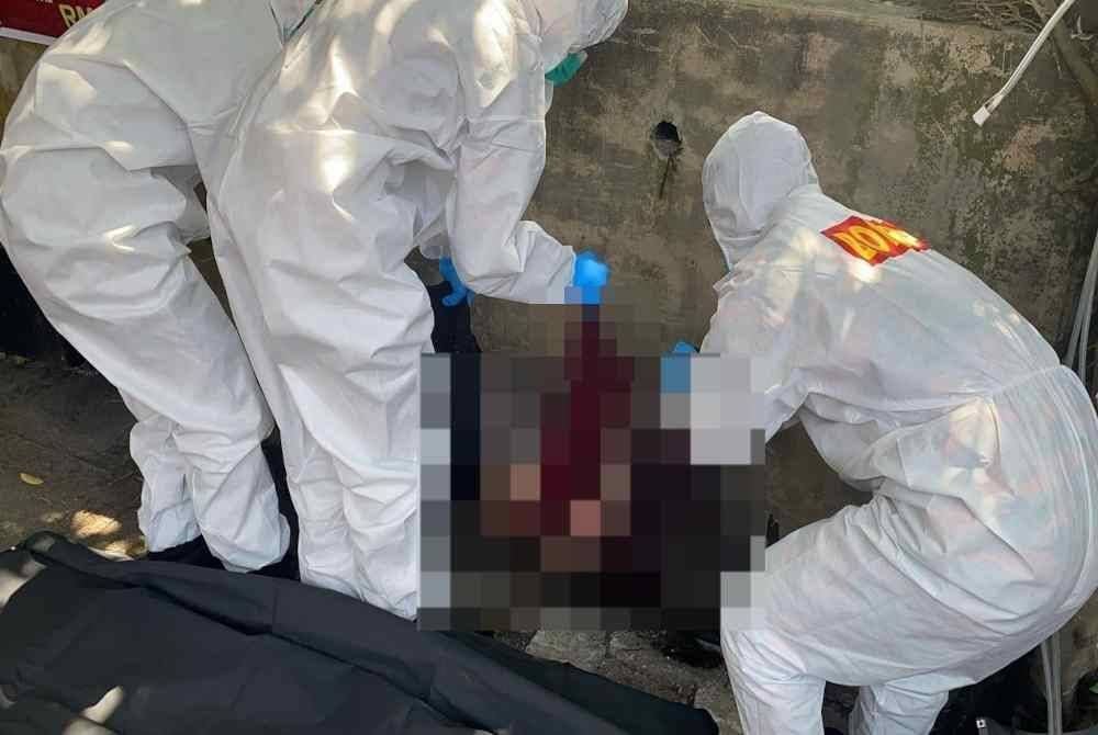 Anggota bomba membantu mengeluarkan mayat mangsa dari dalam longkang. Foto Bomba Perak