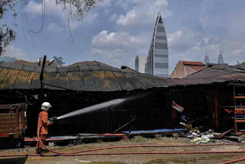 Anggota bomba memadamkan kebakaran melibatkan sebuah kedai perkakasan dan enam unit kedai makan di Jalan Sultan Azlan Shah pada petang Sabtu. Foto Bernama