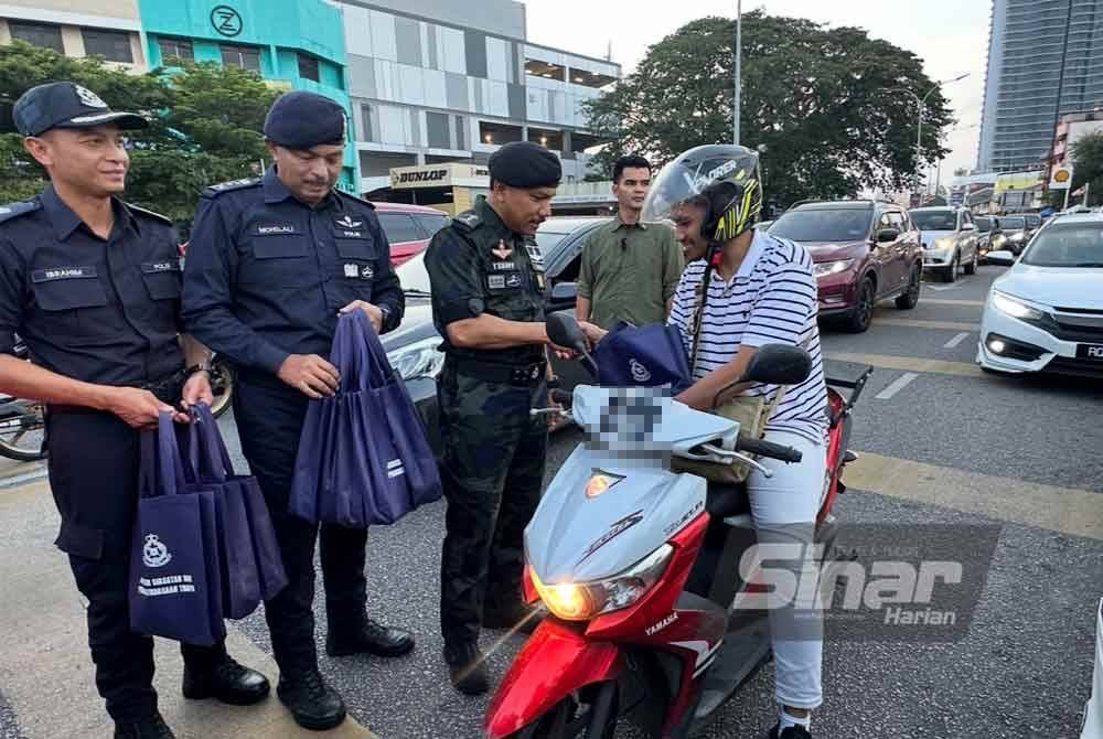 Mohd Yusoff (tiga dari kiri) menyampaikan cenderahati kepada penunggang motosikal.