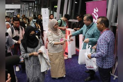 Anthony (dua, kanan) menyampaikan goodies raya kepada penumpang pesawat Batik Air OD 7908 ke Tawau di KLIA Terminal 1 pada Jumaat. Foto Bernama