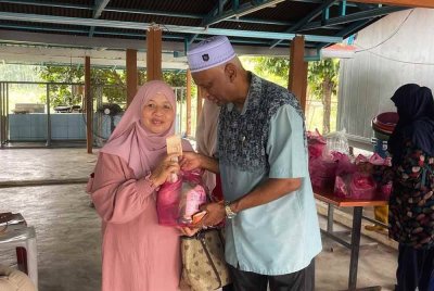 Zainol Abidin (kanan) menyerahkan bantuan kepada penerima terpilih di ladang ternakannya di Jalan Sintok pada Sabtu.