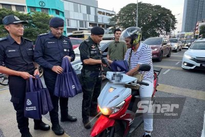Mohd Yusoff (tiga dari kiri) menyampaikan cenderahati kepada penunggang motosikal.