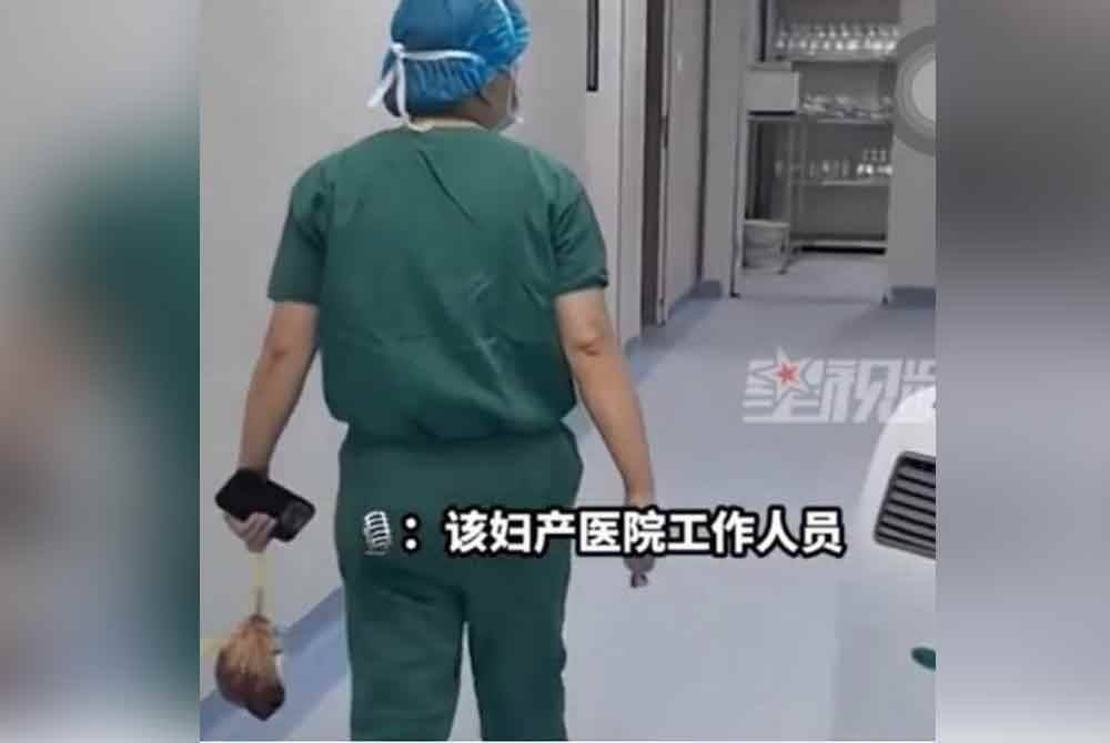 Seorang staf hospital didapat membawa beg plastik berisi uri di sebuah Hospital Bersalin Renhuai Jiudu di Guizhou. - Agensi