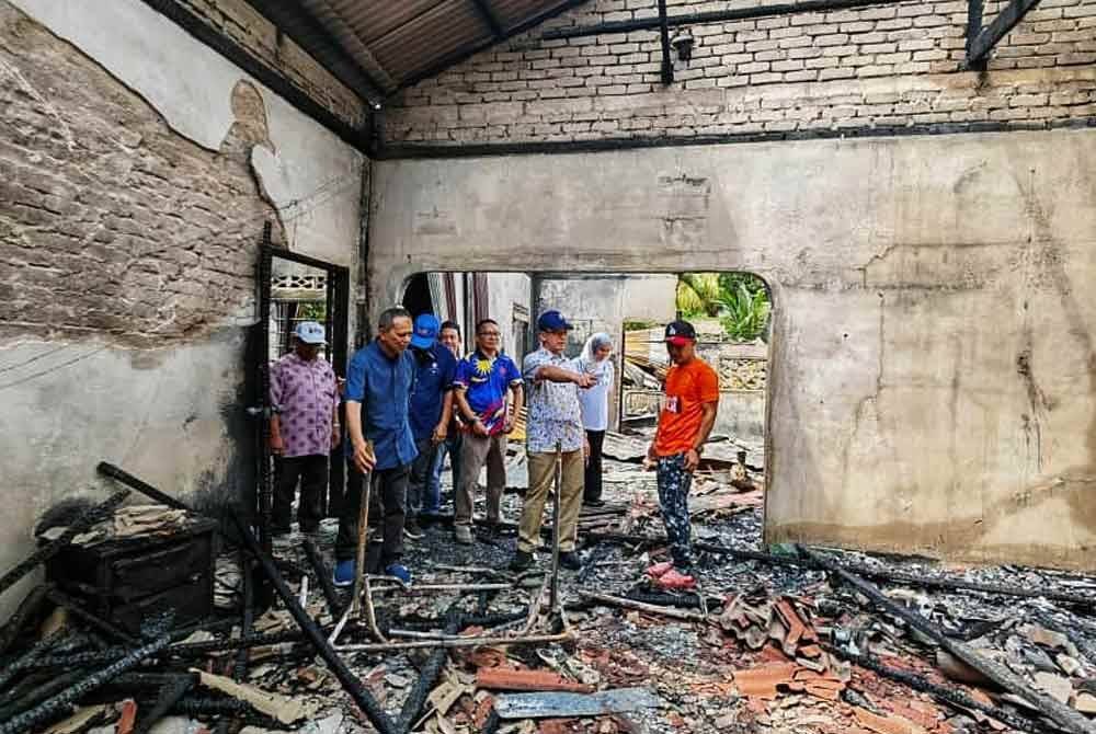 Mohd Banuri (tengah) bersama Razak (kiri) melihat kesan kemusnahan akibat kebakaran terbabit.