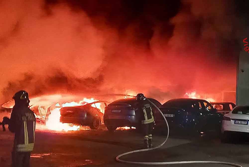 Anggota bomba berusaha memadamkan kebakaran di sebuah pengedar Tesla, di mana 17 kereta musnah atau rosak teruk di Torrenova - Foto: AFP