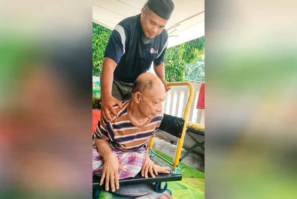 Noor Izam membantu bapa saudaranya untuk bergerak menggunakan papan beroda.
Foto Sinar Harian