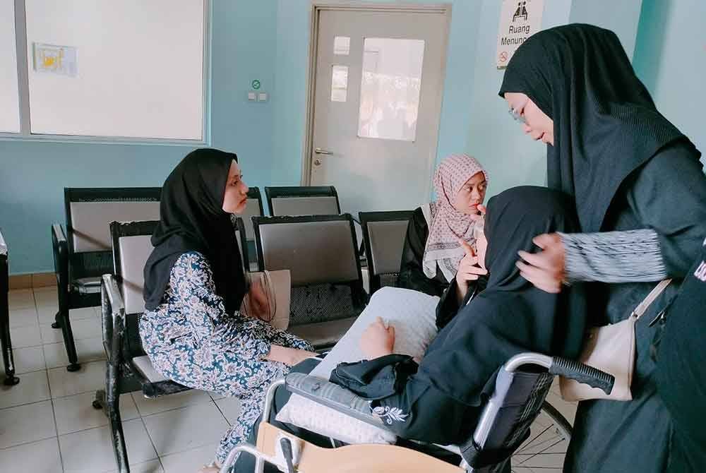 Nor Syahirah (berkerusi roda) ditenangkan keluarga ketika berada Unit Perubatan Forensik Hospital Enche' Besar Hajjah Khalsom (HEBHK) Kluang.