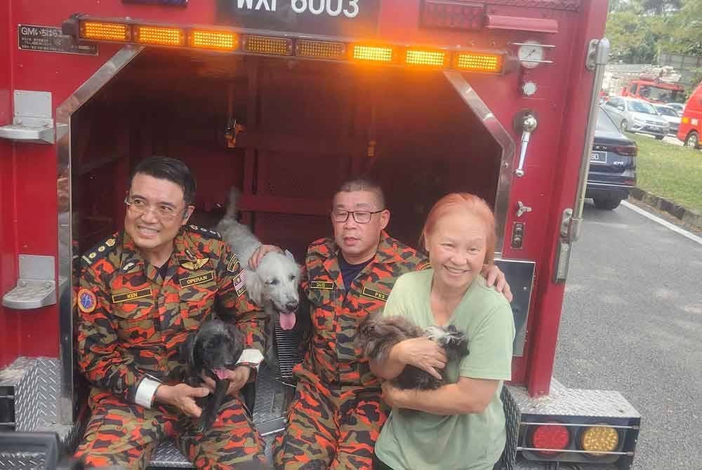 Ken (kiri) bersama pegawai serta penduduk Taman Harmoni selepas berjaya menyelamatkan enam ekor haiwan peliharaan yang terperangkap dalam kediaman.