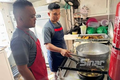 Mohd Saiful (kiri) memantau anggota memasak di kapal. FOTO SINAR HARIAN-ADILA SHARINNI WAHID