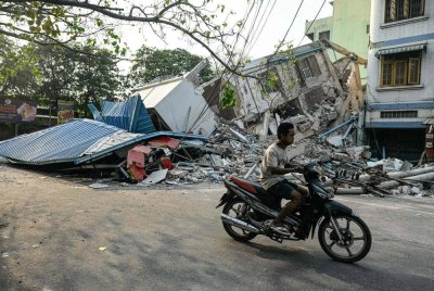 Seorang lelaki menunggang motosikal melalui bangunan yang musnah akibat gempa bumi di Mandalay, Myanmar pada Selasa. Foto AFP