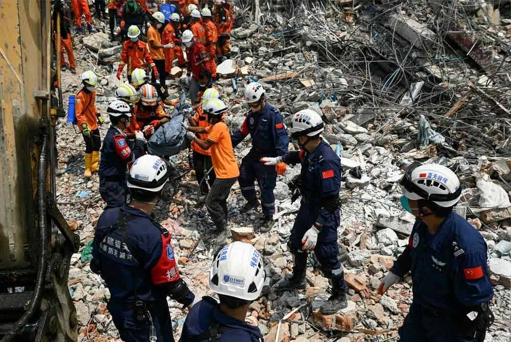 Penyelamat Myanmar dan China membawa mayat mangsa yang terperangkap di bawah runtuhan bangunan 'Sky Villa Condominium development' di Mandalay pada 2 April 2025 - Foto: AFP