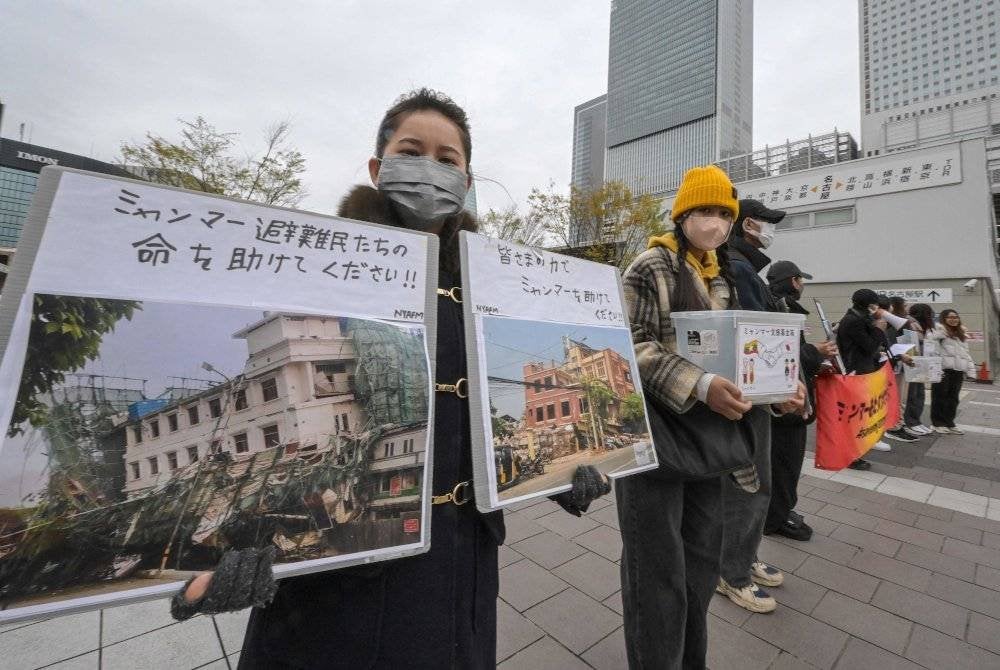 Sukarelawan memegang sepanduk dan papan tanda meminta sumbangan untuk mangsa gempa bumi berukuran 7.7 magnitud baru-baru ini yang melanda Myanmar, di luar stesen kereta api Nagoya pada 1 April 2025. Foto AFP
