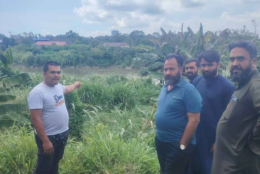 Ahmad Syawal (kiri) menunjukkan lokasi beberapa penduduk di lokasi berhampiran tragedi kebakaran cuba menyeberang sungai untuk mendapatkan pertolongan, pada Selasa.