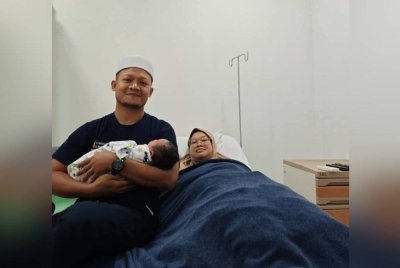 Muhamad Uqbah mengendong bayinya yang baru lahir bersama isteri di hospital.
