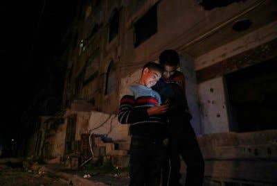 Dua kanak-kanak lelaki melihat telefon bimbit di jalan gelap di Damsyik, Syria. Foto AP