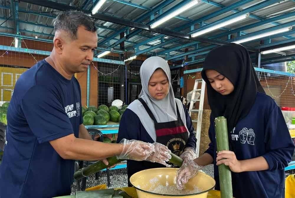 Jeffrey (kiri) menyediakan lemang sebelum dibakar.