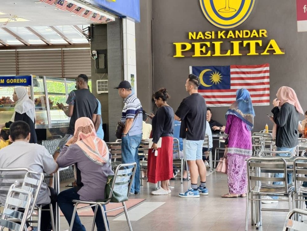 Orang ramai beratur menunggu giliran membeli nasi kandar.