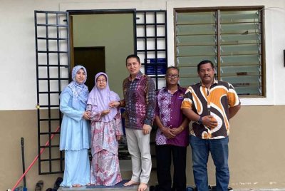 Rogayah (dua, kiri) sebak menerima kunci rumah PPRS yang disampaikan oleh Noor Hariri (tiga, kanan) di Kampung Slow Teliar, Pasir Mas pada Khamis.