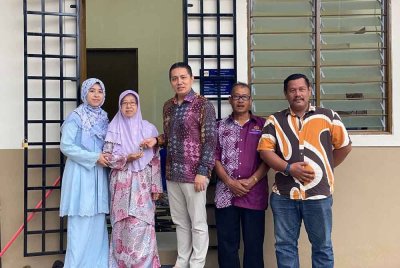 Noor Hariri (tiga,kanan) menyerahkan kunci rumah kepada Rogayah (dua,kiri) menerusi PPRS di Kampung Slow Teliar, Pasir Mas pada Khamis.