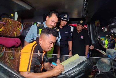 Muhammad Kifli (dua dari kiri) melihat pemandu bas bersedia untuk memulakan perjalanan.