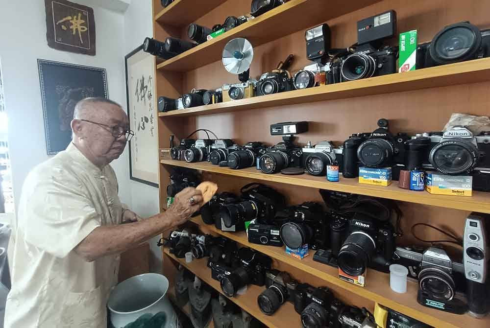Fook Seek membersihkan kamera yang disimpan di rak khas.