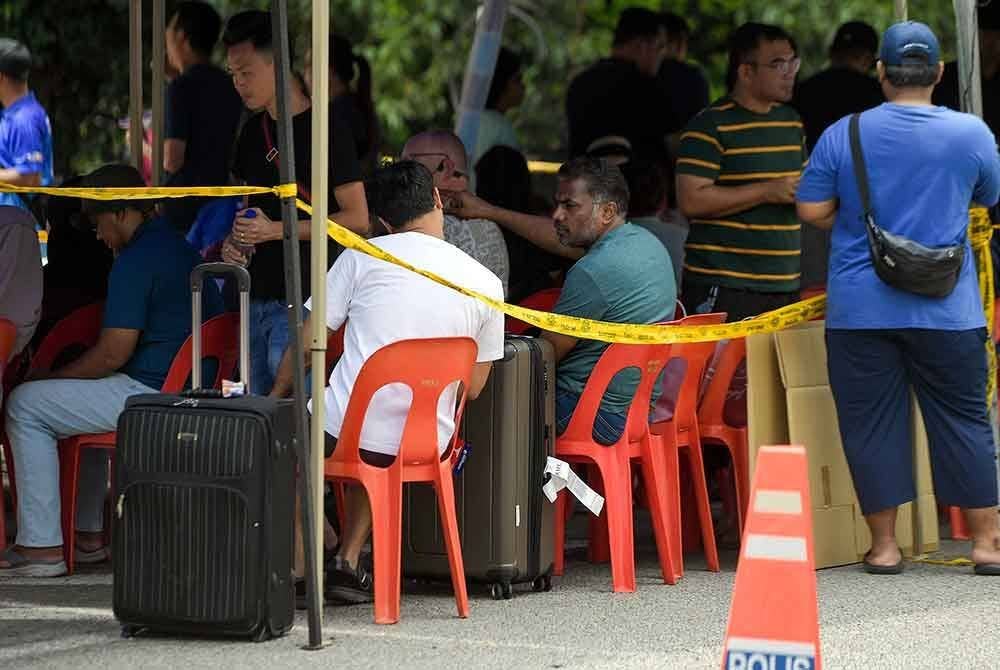 Penduduk yang juga merupakan mangsa kebakaran dilihat menunggu giliran untuk pulang ke kediaman masing-masing bagi mengambil barangan keperluan serta dokumen penting pada Jumaat. Foto Bernama