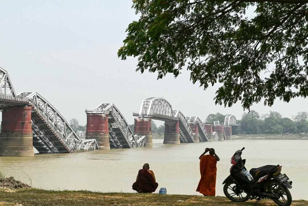 Seorang sami merakam gambar Jambatan Ava merentasi Sungai Irrawaddy yang runtuh akibat gempa dahsyat itu. Foto AFP