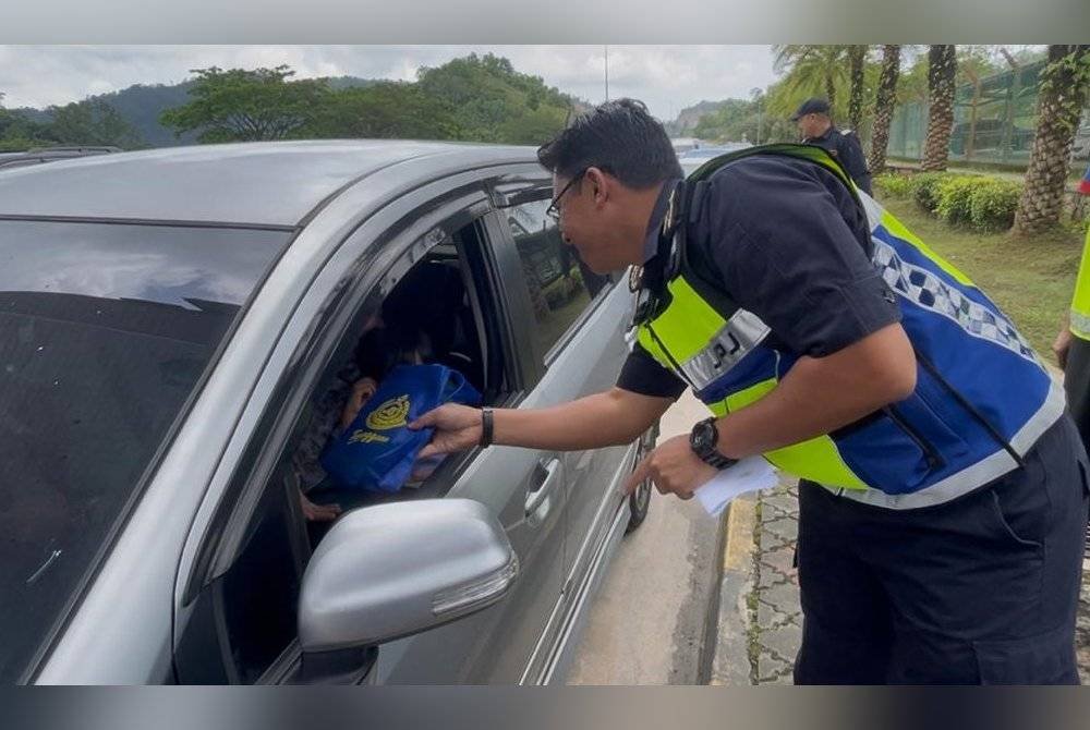 Mohd Zamri menyerahkan buah tangan kepada pengguna jalan raya sempena Ops Khas HRA 2025 di Plaza Tol Gemuruh, di Kuala Terengganu, pada Sabtu.