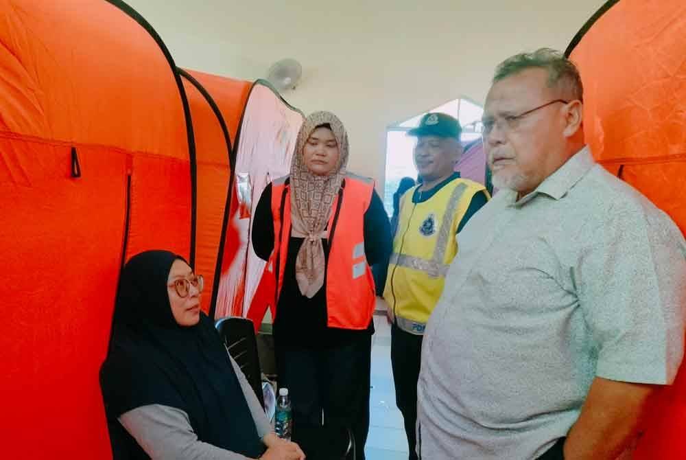 Aminolhuda (kanan) melawat mangsa banjir di PPS SMK Sri Gading pada Ahad.