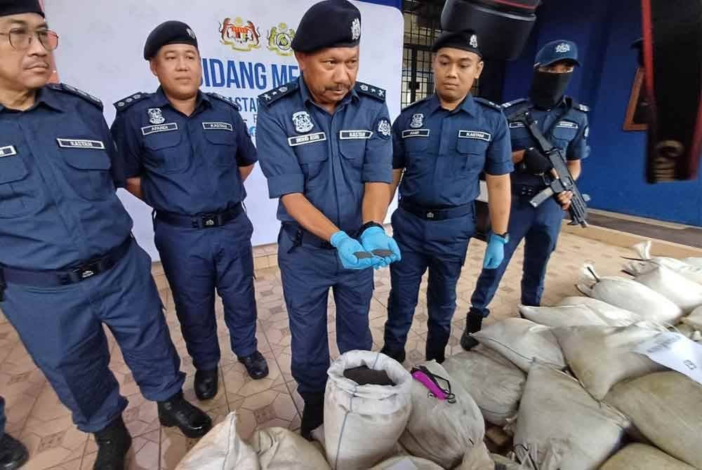 Mohd Asri (tengah) menunjukkan bijih timah yang dirampas hasil kejayaan JKDM mematahkan cubaan pemunggahan bijih timah di sebuah jeti haram.