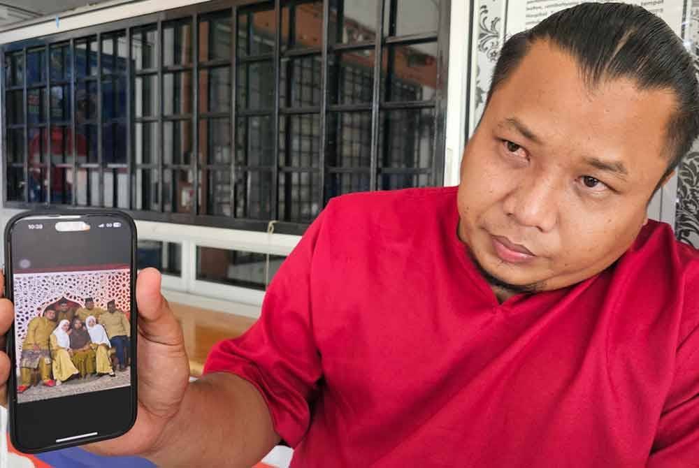 Rifaai menunjukkan gambar Allahyarham Mohd Fakhrurazi dan ahli keluarganya yang dirakamkan di sebuah studio di Kuala Kangsar, Sabtu lalu.