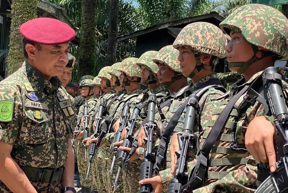Muhammad Hafizuddeain (kiri) memeriksa barisan semasa mengadakan lawatan ke kawasan operasi 8 Briged sempena Aidilfitri di Pos Tok'O, Rantau Panjang pada Isnin.