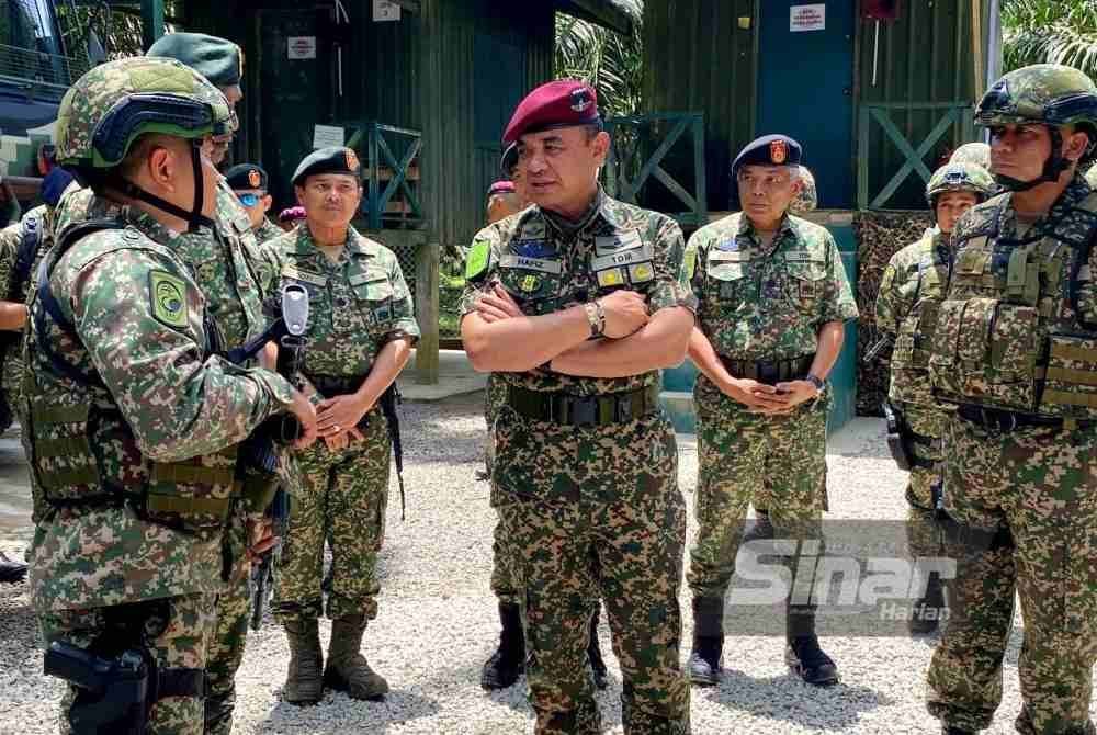Muhamad Hafizuddeain (tengah) mendengar taklimat semasa mengadakan lawatan ke kawasan operasi 8 Briged sempena Aidilfitri di Pos Tok' O di Rantau Panjang pada Isnin.