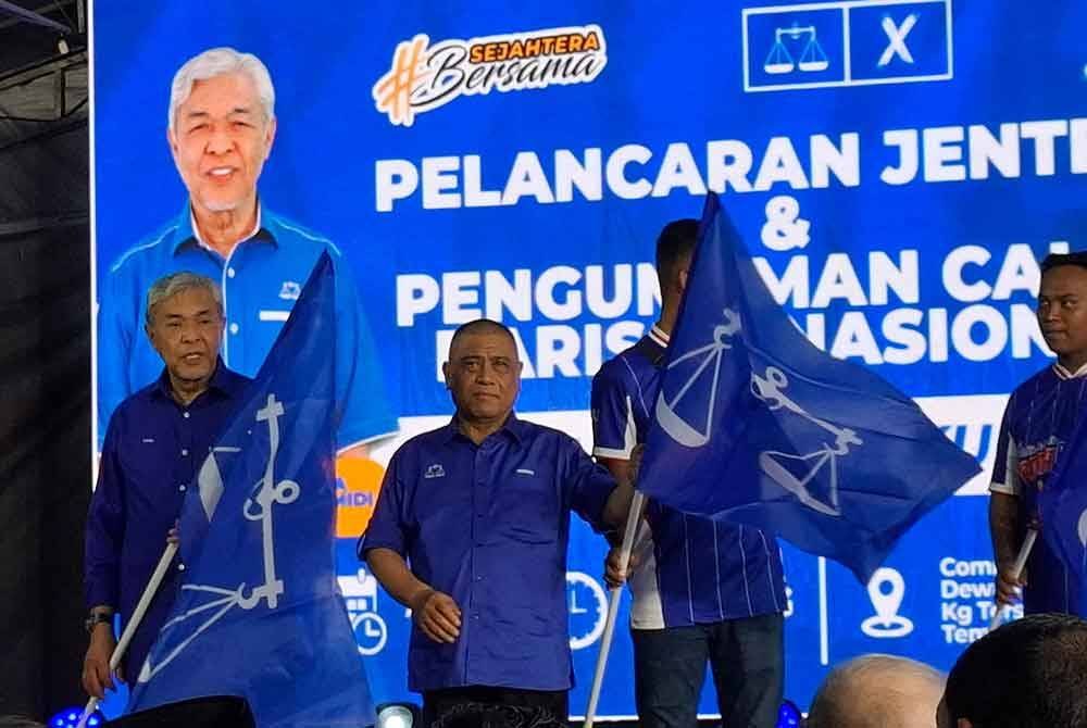 Saarani (dua dari kiri) dan Ahmad Zahid (kiri) menyerahkan bendera BN kepada wakil jentera parti sempena Pelancaran Jentera dan Pengumuman Calon BN N.28 Ayer Kuning di Pusat Arahan BN, Kampung Tersusun Haji Tahir, Temoh pada Isnin.