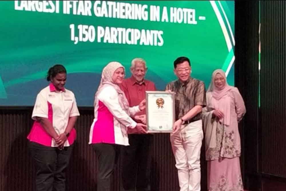 Siti Hajar (dua, kiri) menyampaikan sijil Malaysia Book of Records bagi perhimpunan iftar terbesar di sebuah hotel kepada Alvin disaksikan Kamarudin (tengah).