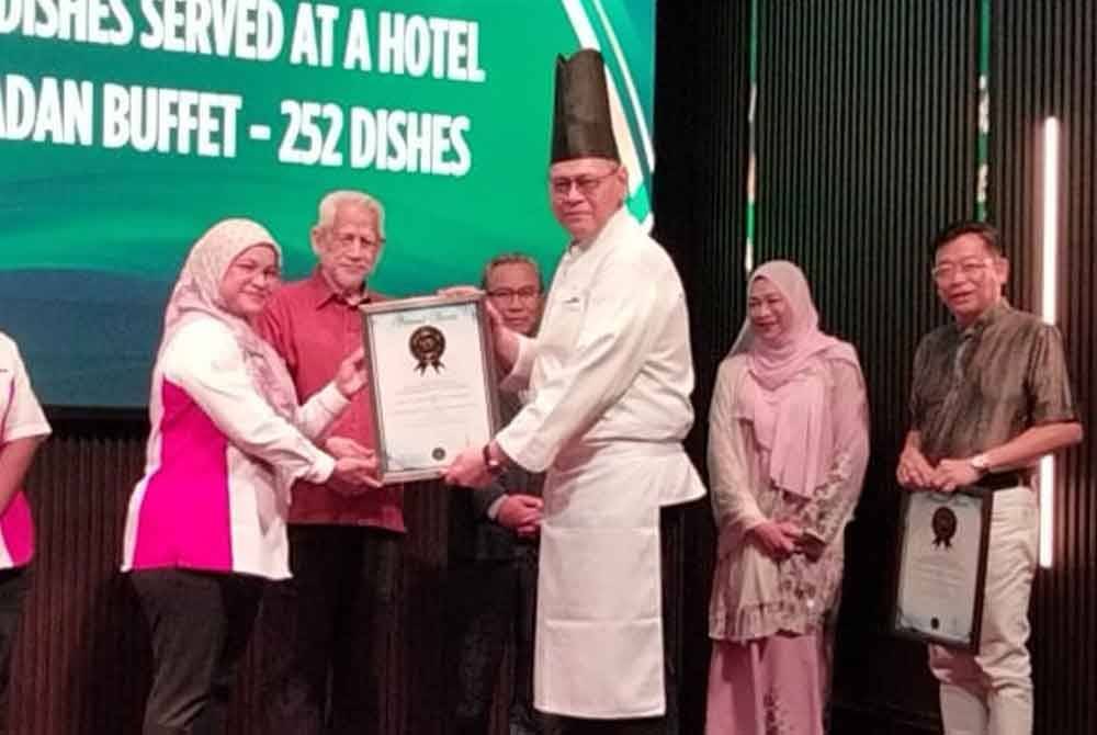 Siti Hajar (dua kiri) menyampaikan sijil Malaysia Book of Records bagi gerai makanan jalanan dalam dewan terpanjang di sebuah hotel kepada Izan disaksikan oleh Kamarudin (tiga, kiri).
