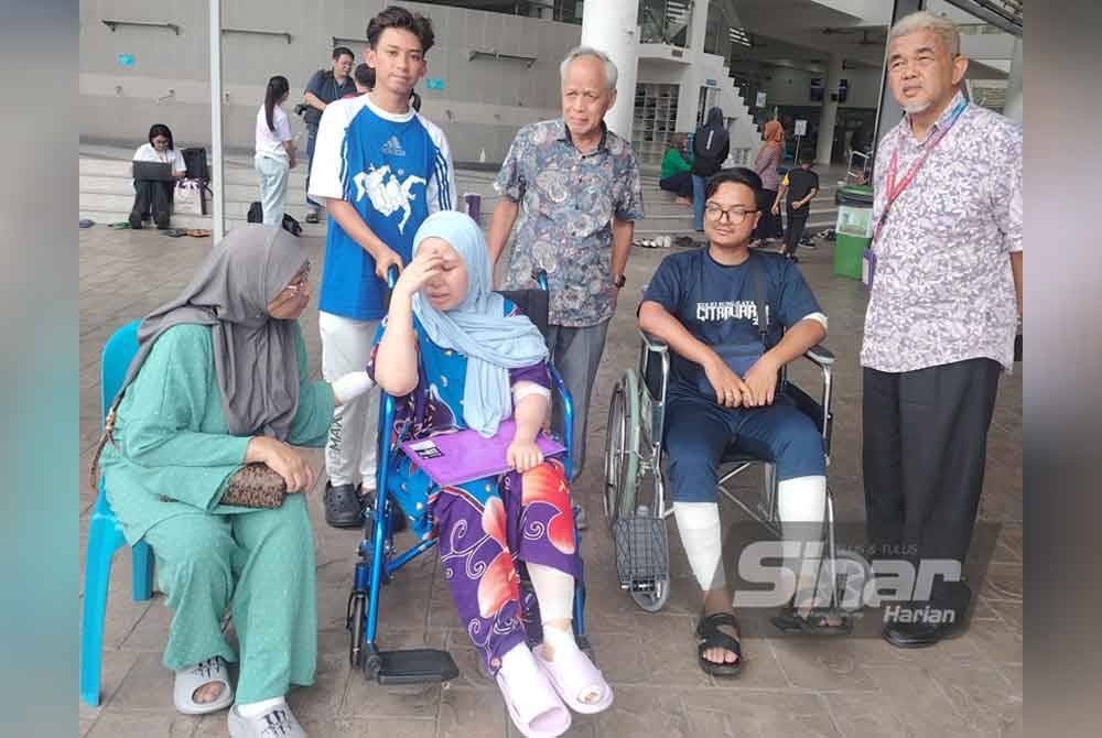 Muhammad Nasir (berdiri, dua dari kanan) dan Hashim (berdiri, kanan) menziarahi Muhammad Amirul (duduk, kanan) dan keluarganya di PPS Dewan Putra Heights pada Isnin.